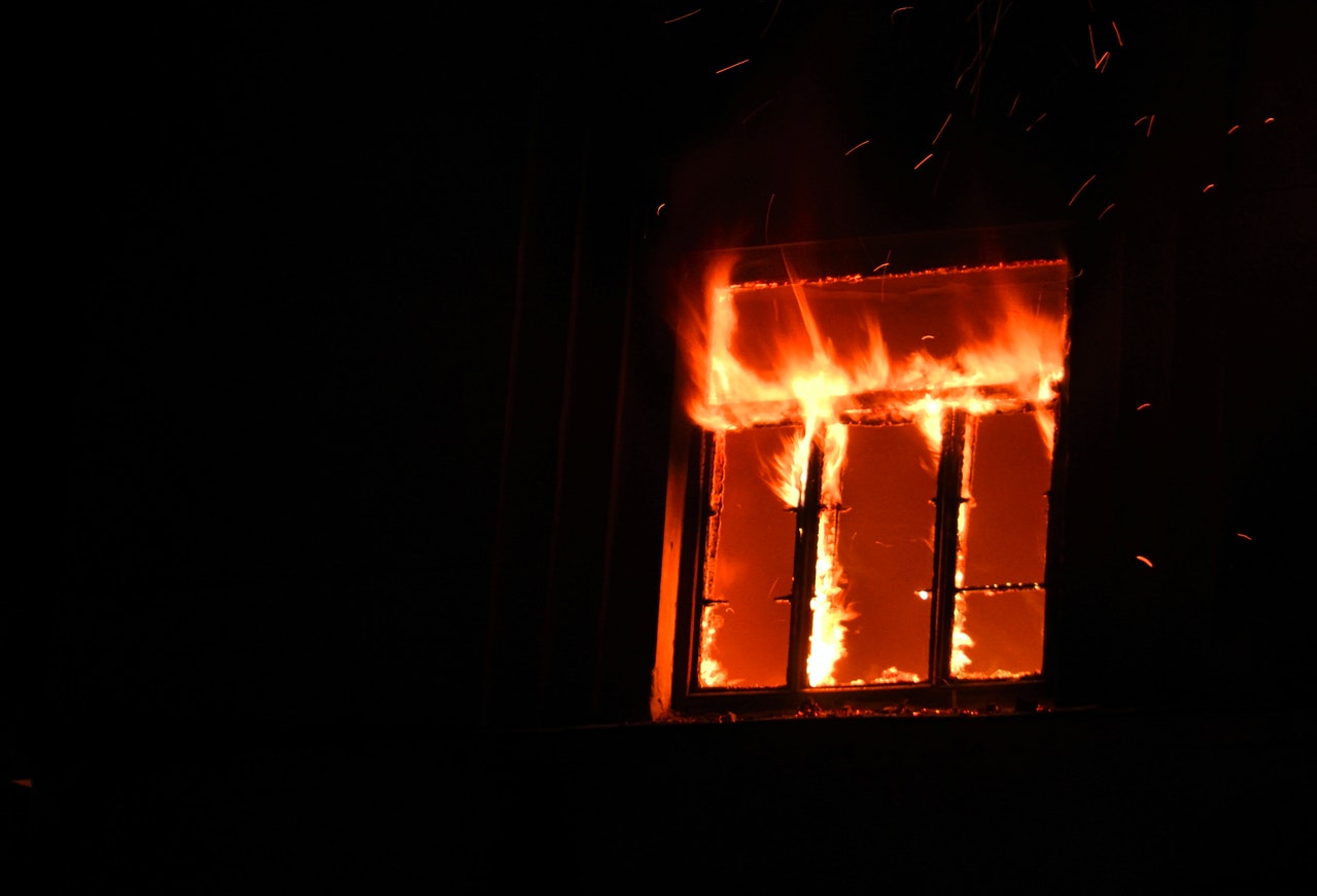 Home on fire at night, with flames coming out of a window